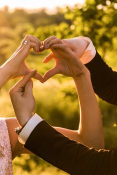 the bride and groom show the hand sign of the heart with an arrow