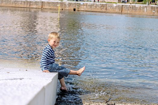 Little preschool boy posing on shore outdoors