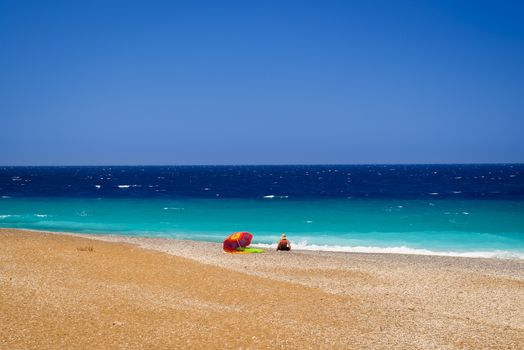 Sunbather calmly relaxing by the Deep Blue Seas at the North tip of Rhodes where the Aegean and Mediterranean Meet