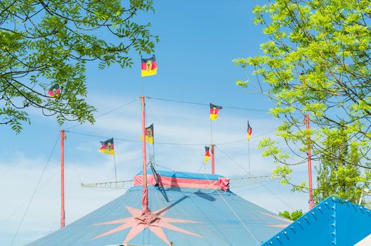 Beautiful colorful circus tent with flags in front of a bright blue sky.
