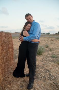 Elegant young couple on a romantic walk in a field of blossoming lavender and oblique hay.