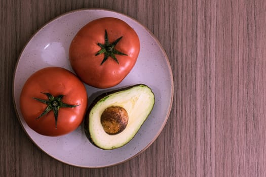 A dish with two big tomatoes and half avocado