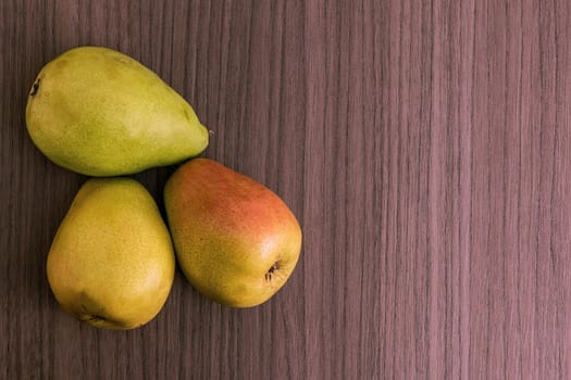 Three succulent ripe pears over wood background