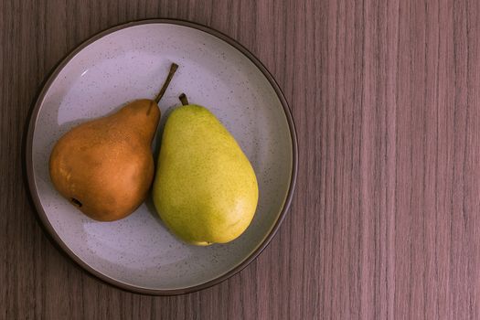 A bowl with a golden pear and a green pear