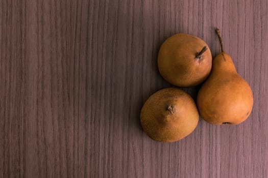Three succulent golden pears over wood background
