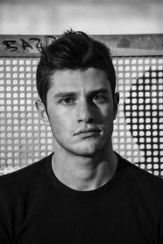 Headshot of attractive young man looking at camera, against grid background, black and white shot