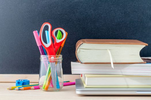 Back to school concept with school supplies laptop ,book, pen,mouse,and colored pencil on wooden table .