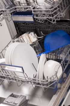 Dishwasher loades in a kitchen with clean dishes and blue light