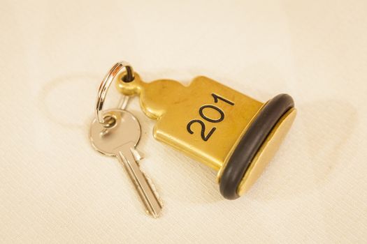 Hotel Room Key lying on Bed with keyring golden