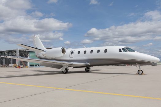 Aircraft learjet Plane in front of the Airport with cloudy sky and sun