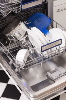 Dishwasher loades in a kitchen with clean dishes and blue light