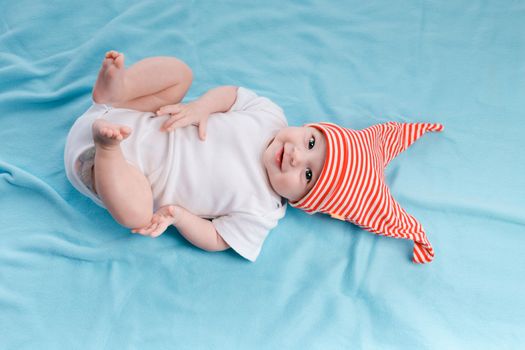 Baby in hat lying on a blue plaid