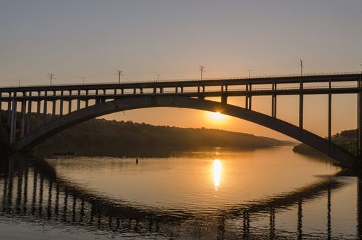 road and rail split-level bridge over the river on a background of blue sky in the city