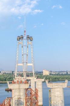 the construction of a bridge across the river with the supports, structural elements, cranes