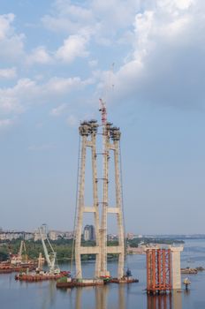 the construction of a bridge across the river with the supports, structural elements, cranes