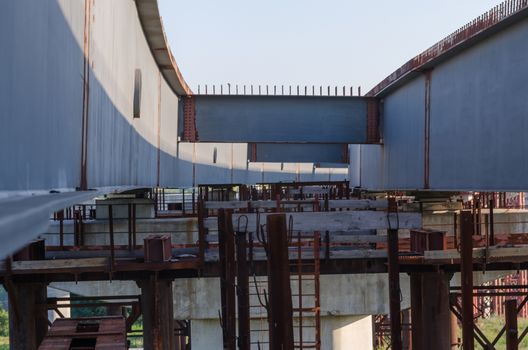 the construction of a bridge across the river with the supports, structural elements, cranes