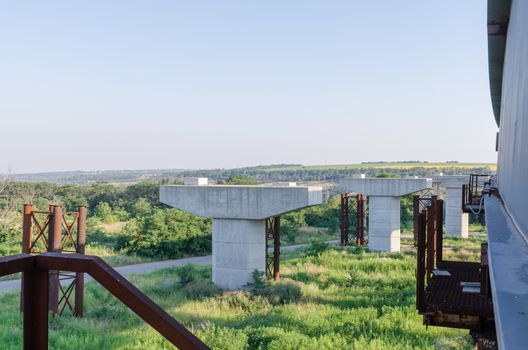 the construction of a bridge across the river with the supports, structural elements, cranes