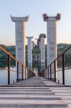 the construction of a bridge across the river with the supports, structural elements, cranes