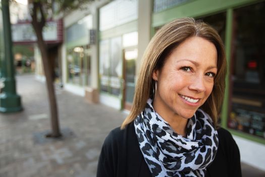 Mature female business owner standing in front of store