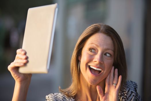 Beautiful single Caucasian woman waving at her tablet computer