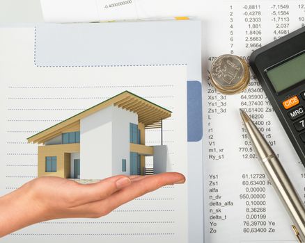 Humans hand holding house with pen and coins