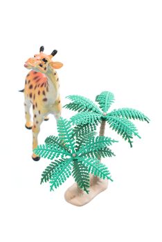 A small toy giraffe with trees isolated on a white background.