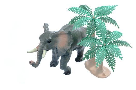 A small toy elephant with trees isolated on a white background.