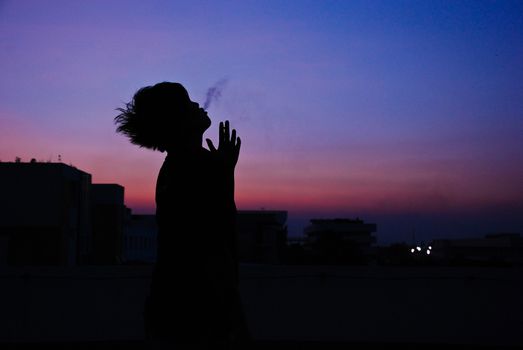 silhouette of man smoke cigarette on top of building evening sunset blue sky so alone but art beautiful