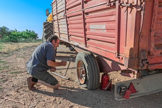 Man repair tire of trailer in farm