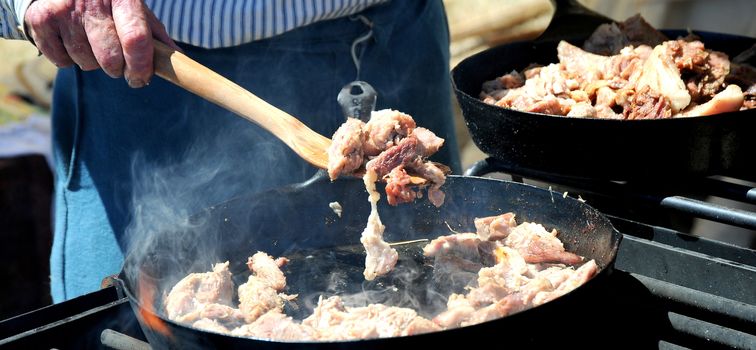 Man cooking chicken using dutch oven pots and pans.