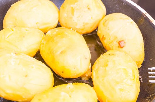 Roasted potatoes with bacon in a skillet, close-up.