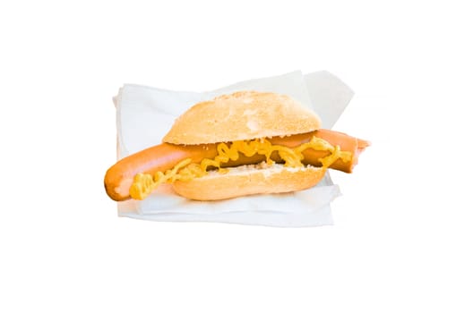 Sausage with mustard in bread roll and a white napkin lying on a brown wooden table. Against a white background