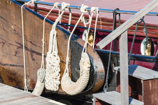 Close up of a ship's rail of an old wooden sailing boat. rope to a sailing mast.