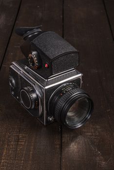 vintage black film camera on the brown background of natural wood with the lens