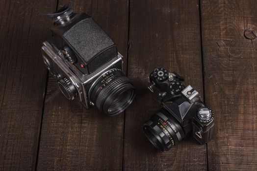 vintage black film camera on the brown background of natural wood with the lens