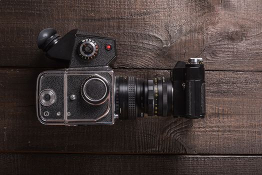 vintage black film camera on the brown background of natural wood with the lens