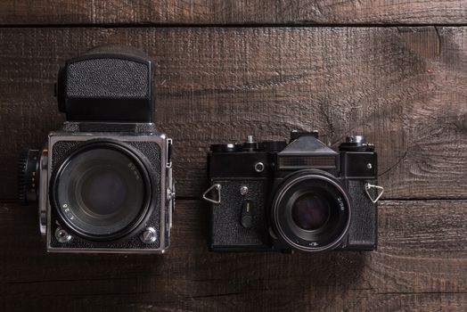 vintage black film camera on the brown background of natural wood with the lens