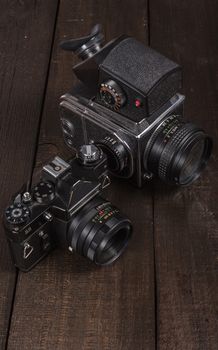 vintage black film camera on the brown background of natural wood with the lens