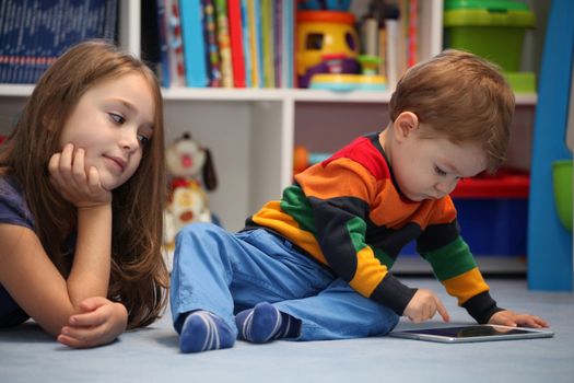 Disappointing girl with her little brother using a digital tablet computer