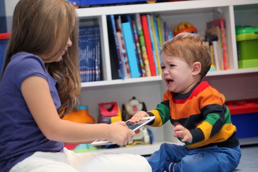 girl and her little brother crying and arguing with a digital tablet computer