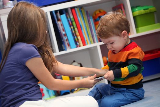 girl and her little brother crying and arguing with a digital tablet computer