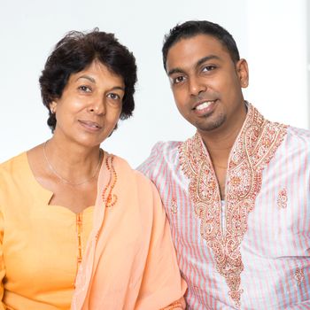 Portrait of happy Indian family at home. Beautiful mature 50s Indian mother and her 30s grown son.