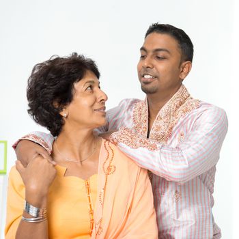 Portrait of happy Indian family interacting at home. Mature 50s Indian mother and her 30s grown son.