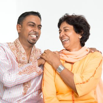 Portrait of happy Indian family having fun at home. Mature 50s Indian mother and 30s grown son laughing happily.