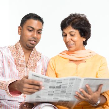 Portrait of Indian family reading newspaper together at home. Mature 50s Indian mother and 30s grown son.