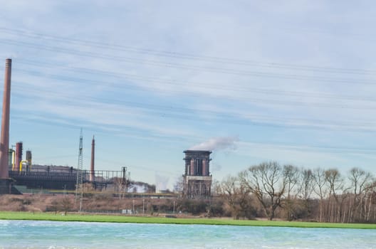 Old power plant on a river against a blue sky.
