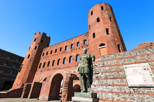 Roman statue of Julius Caesar and ancient ruins of Palatine Towers in Torino, Piemonte, Italy