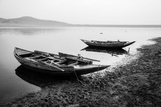 Rural Indian fishing boats tied at the shore of a river at sunset 