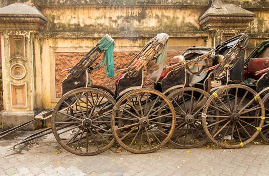 Side view of hand pulled cart rickshaws parked together.