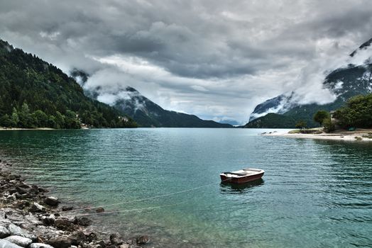 lake of Molveno in a cloudy summer afternoon with boat, Trentino - Italy